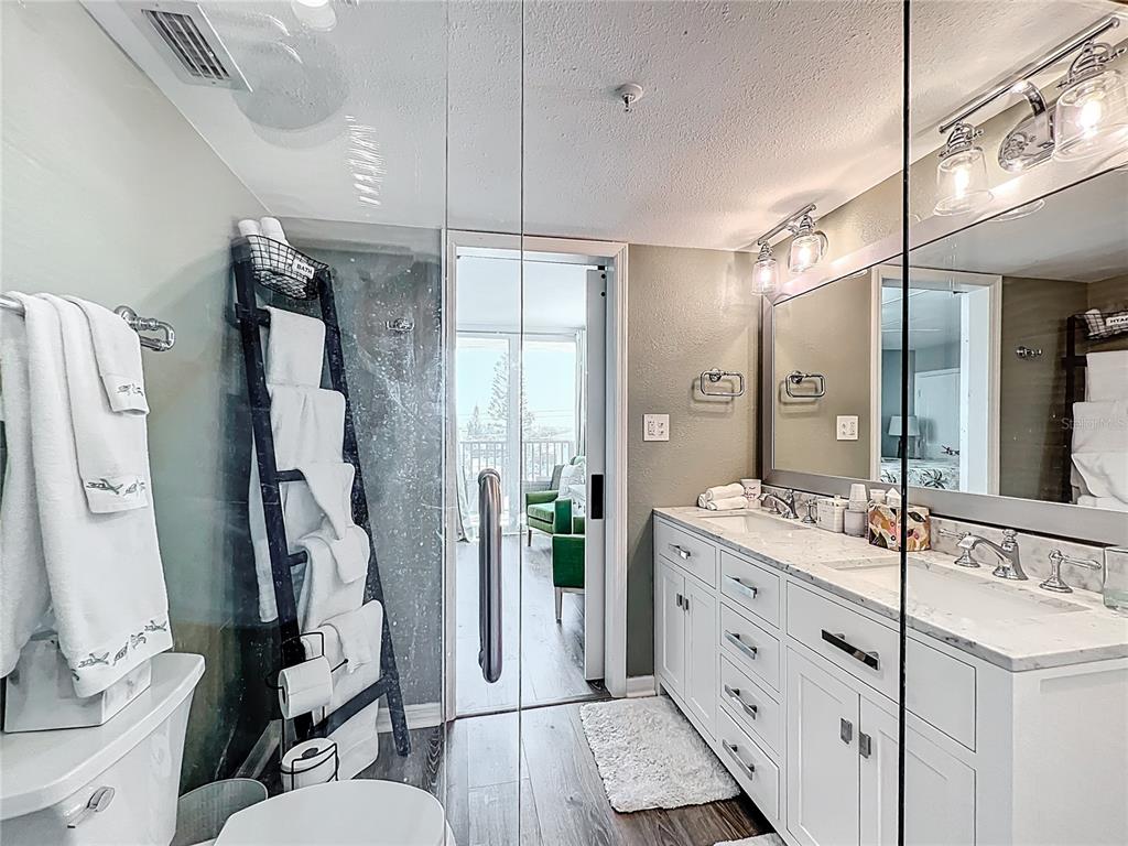 14146 Gulf Boulevard, Unit 3A Madeira Beach, FL 33708 - Photo 20 of 29 a bathroom with a double vanity sink toilet mirror and shower