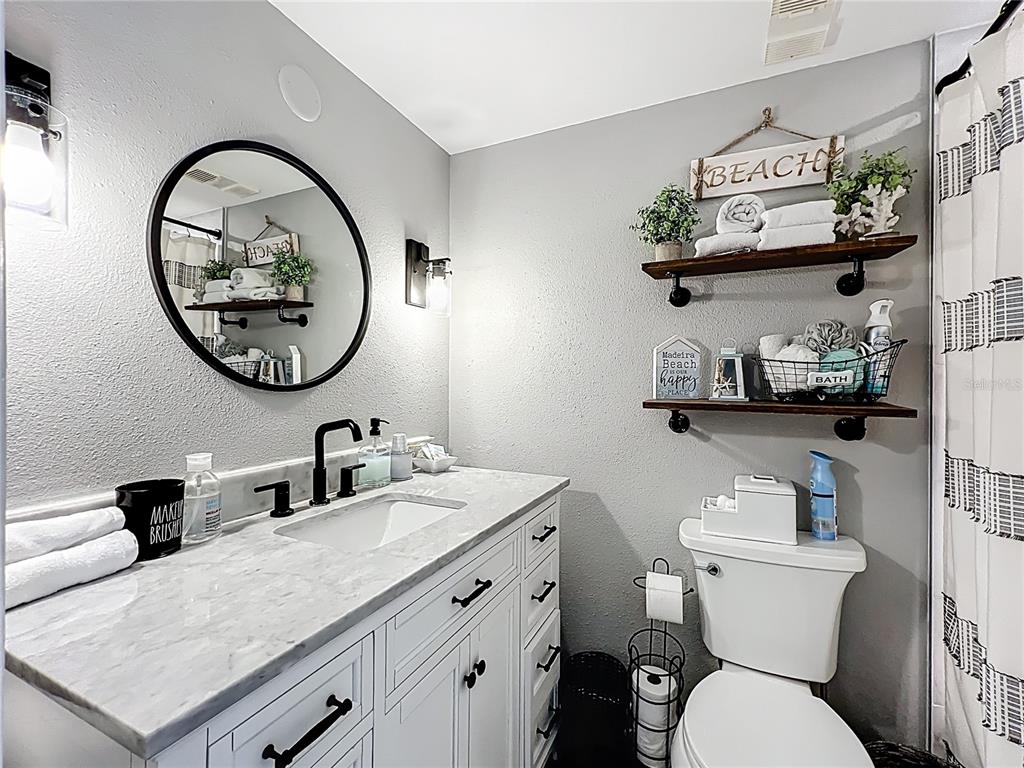 14146 Gulf Boulevard, Unit 3A Madeira Beach, FL 33708 - Photo 24 of 29 a bathroom with a toilet a sink and a mirror