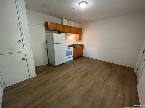 a kitchen with a refrigerator and wooden floor
