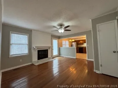 a view of an empty room with wooden floor fireplace and a window