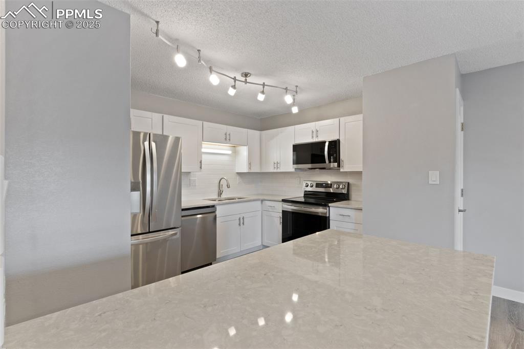 4435 Hunting Meadows Circle Colorado Springs, CO 80916 - Photo 7 of 15 Light & bright kitchen with bright quartz countertops and stainless steel appliances