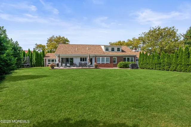 a view of house with a big yard and large trees