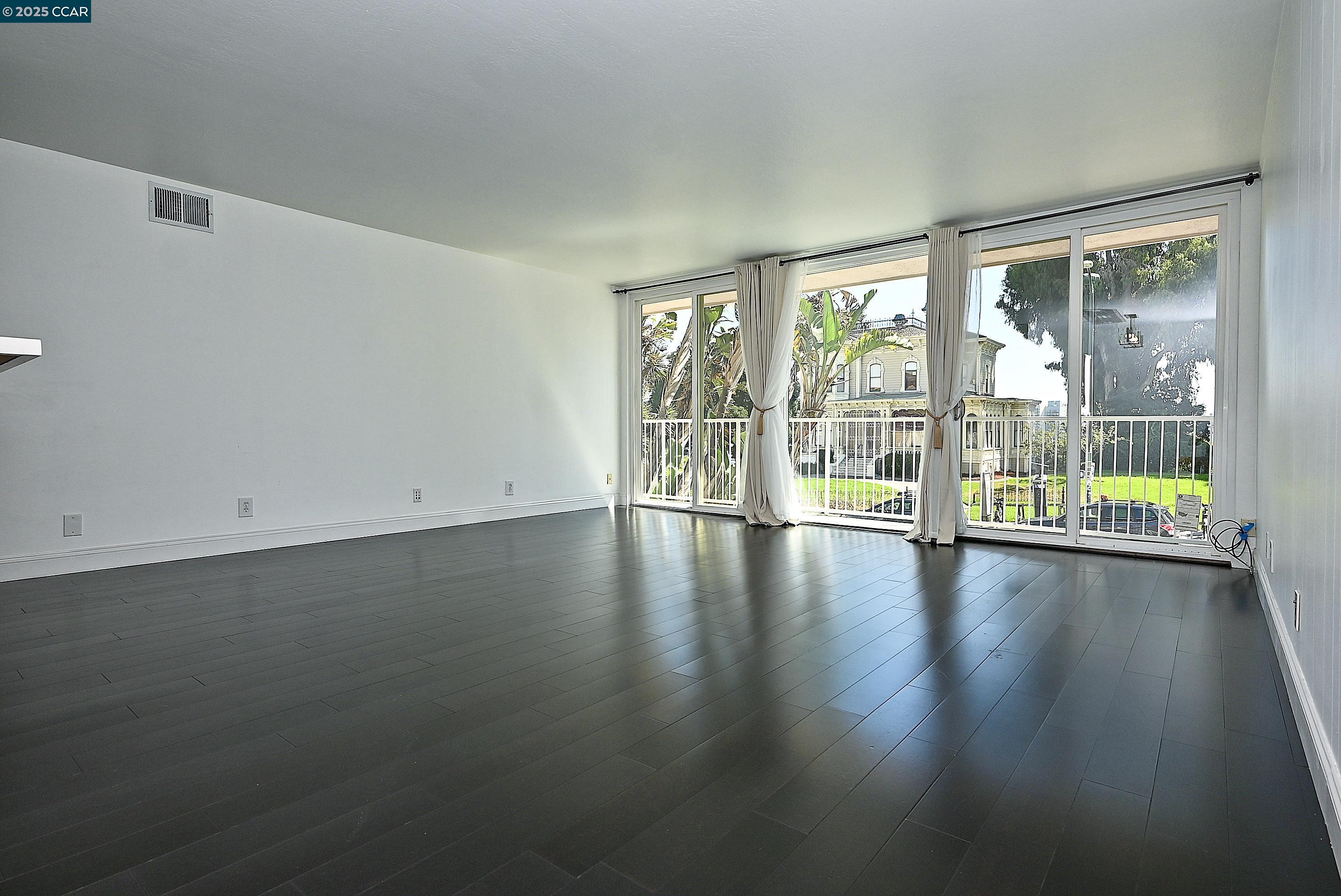 1425 Lakeside Drive, Unit 101 Oakland, CA 94612 - Photo 7 of 36 an empty room with wooden floor and windows