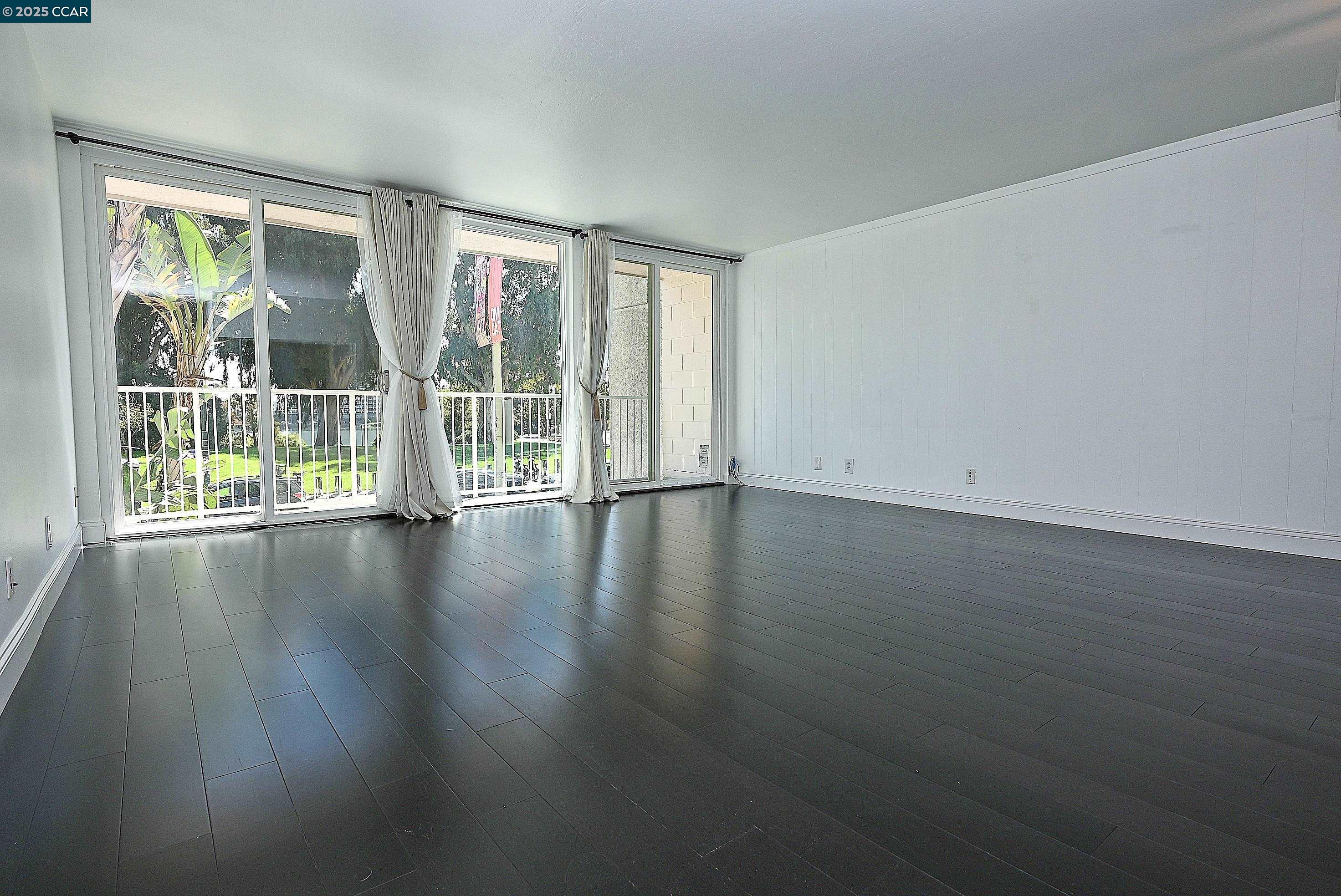 1425 Lakeside Drive, Unit 101 Oakland, CA 94612 - Photo 9 of 36 an empty room with wooden floor and windows