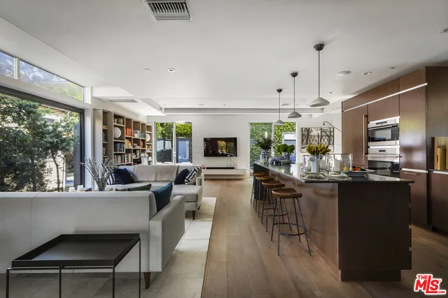 a living room with stainless steel appliances kitchen island granite countertop furniture a flat screen tv and a large window