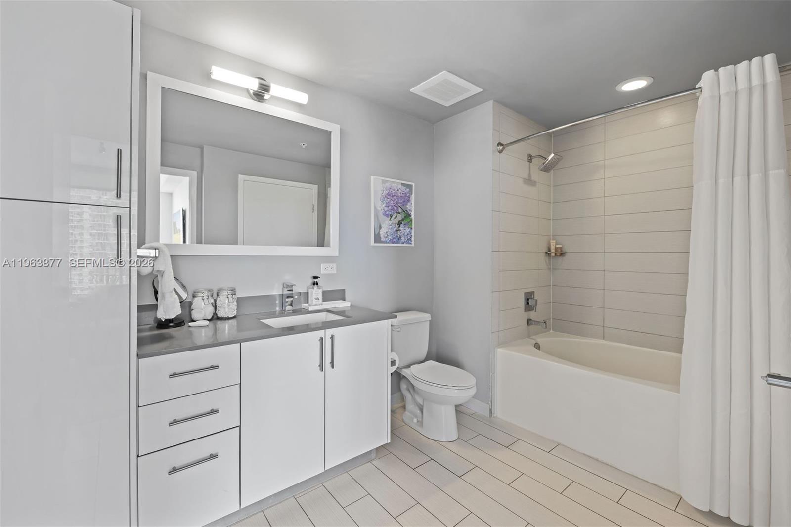 999 Southwest 1st Avenue, Unit 2303 Miami, FL 33130 - Photo 5 of 44 a bathroom with a granite countertop sink a toilet mirror and bathtub