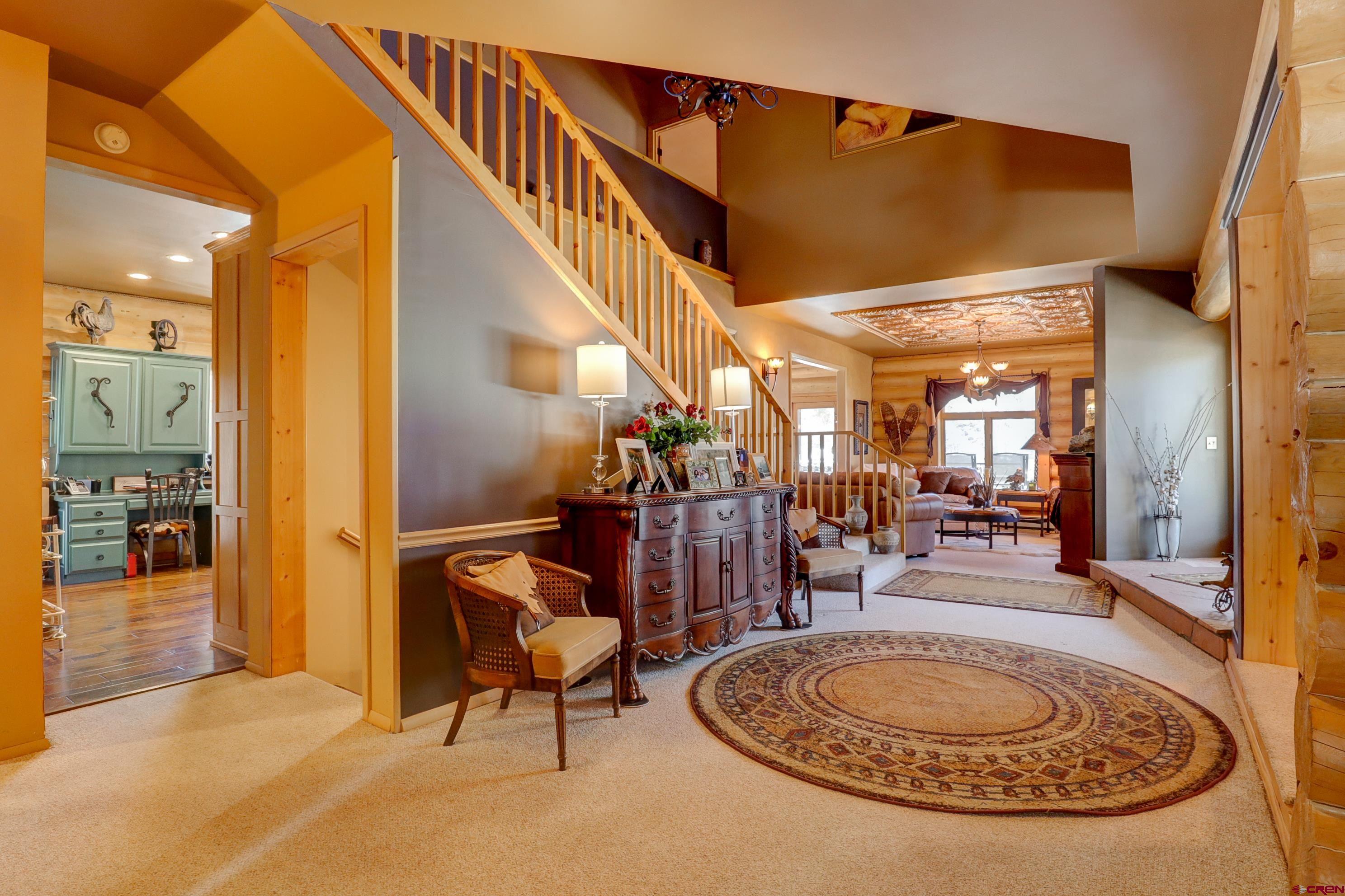 18656 Highway 145 Dolores, CO 81323 - Photo 11 of 45 Carpeted entrance foyer with stairs, an inviting chandelier, and a towering ceiling