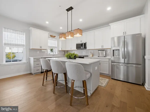 a kitchen with stainless steel appliances a table chairs refrigerator and microwave