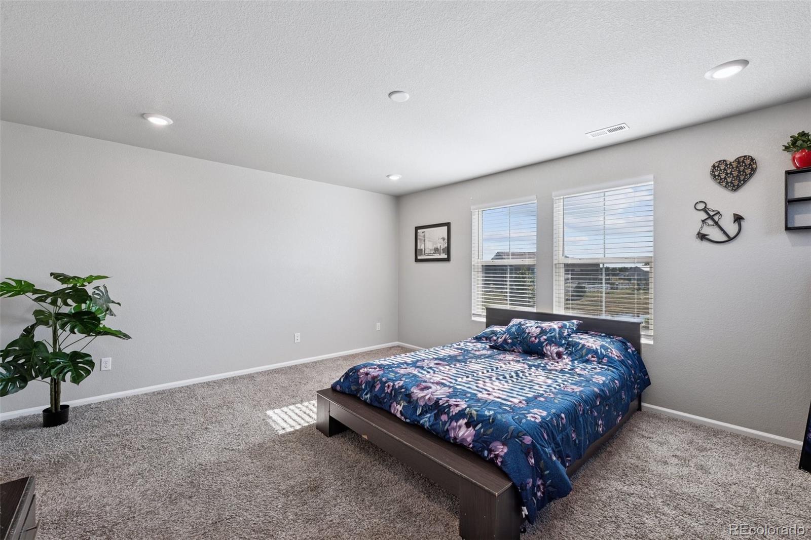 5097 Buckwheat Road Brighton, CO 80640 - Photo 14 of 28 a bedroom with a large bed and a potted plant
