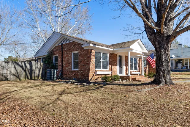 a view of a house with a large tree and wooden fence