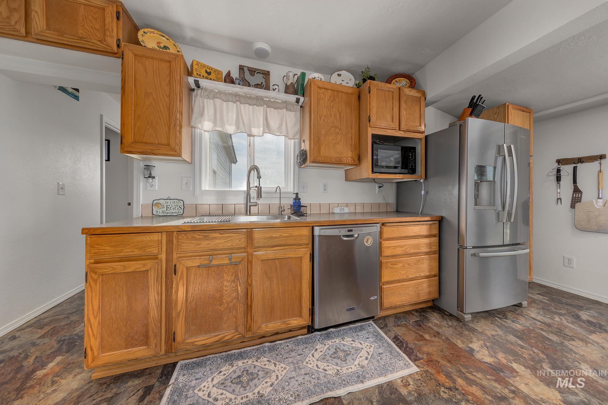 4631 Rolland Road Ontario, OR 97914 - Photo 7 of 43 Wood-finish flooring, ample wood cabinetry, stainless steel appliances, and a tile backsplash