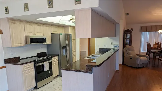 a kitchen with stainless steel appliances kitchen island granite countertop a refrigerator a stove and a sink with wooden floor