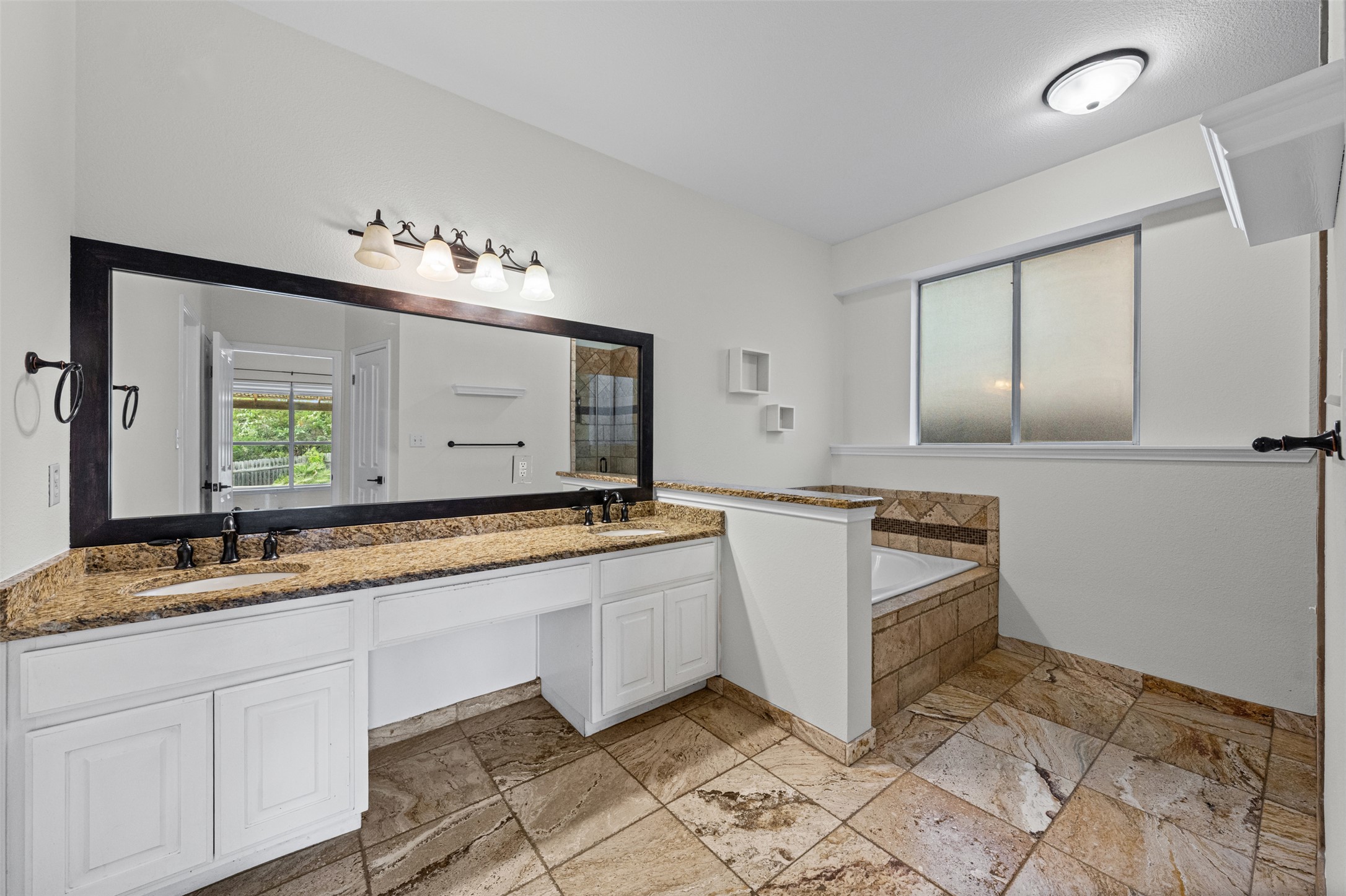 8820 Colberg Drive Austin, TX 78749 - Photo 18 of 35 Tile flooring and granite countertops complement this well-lit bathroom with a deep soaking tub.