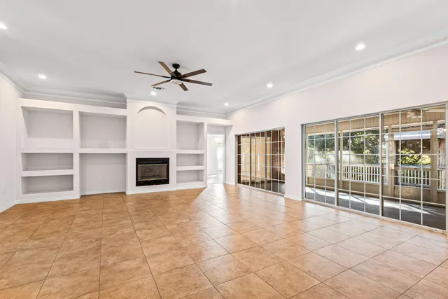 a view of a livingroom with a fireplace a ceiling fan and windows