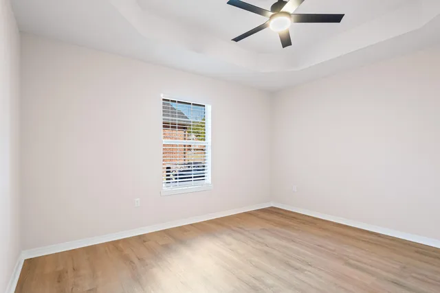 an empty room with wooden floor and ceiling fan