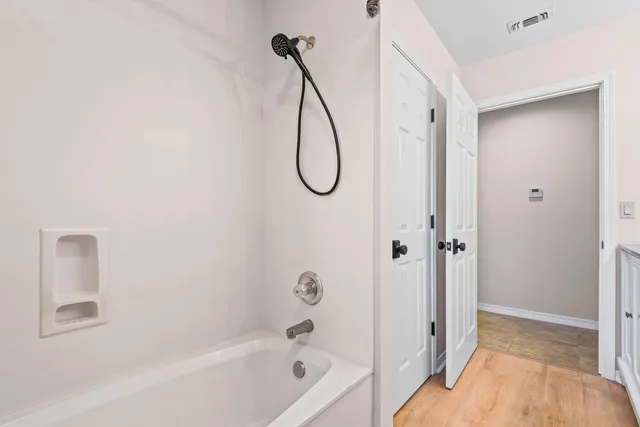 a view of an empty room with wooden floor and a window