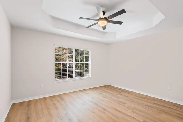 an empty room with wooden floor and a ceiling fan