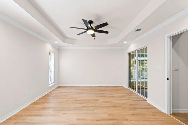 a view of empty room with wooden floor and ceiling fan