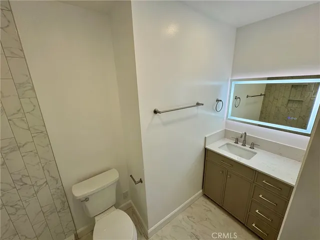 a bathroom with a granite countertop toilet sink and mirror