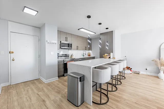 a kitchen with stainless steel appliances a dining table chairs and wooden floor