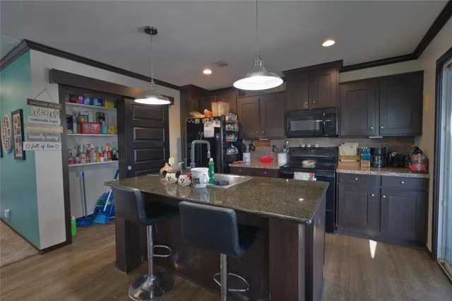 a kitchen with stainless steel appliances granite countertop a refrigerator a stove top oven a sink dishwasher and white cabinets with wooden floor