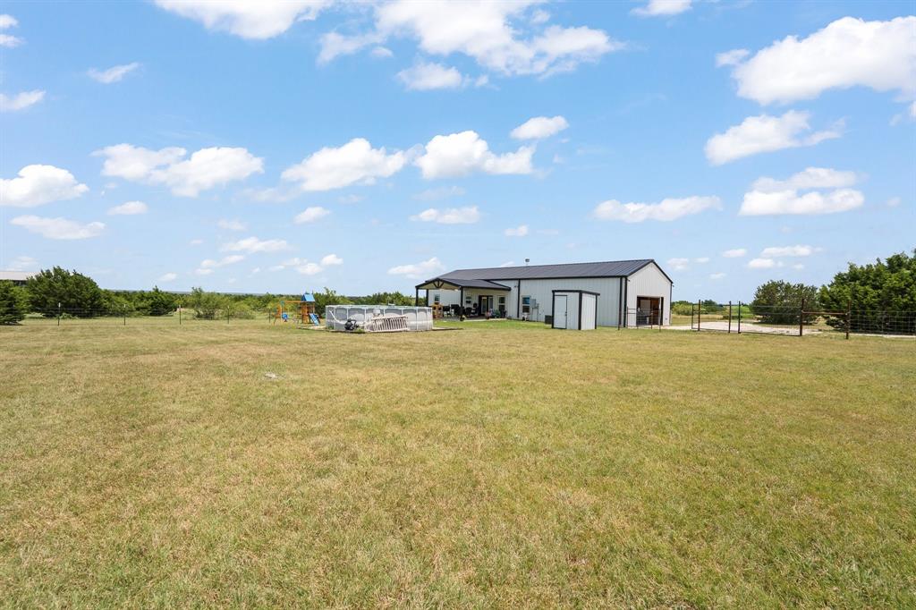 1031 Augustus Court Rio Vista, TX 76093 - Photo 24 of 30 Expansive outdoor space featuring a metal-sided residence with a covered patio, a detached storage shed, and perimeter fencing
