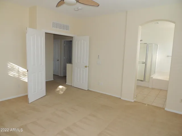 a view of an empty room and chandelier fan