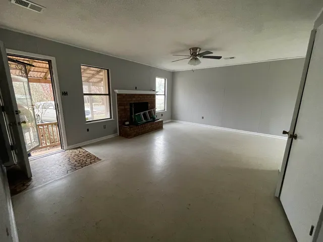 wooden floor in an empty room with a fireplace and a window