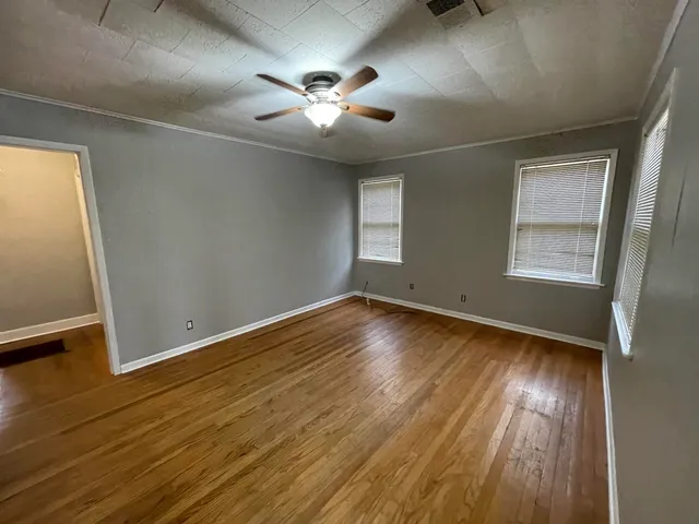 a view of empty room with wooden floor and fan
