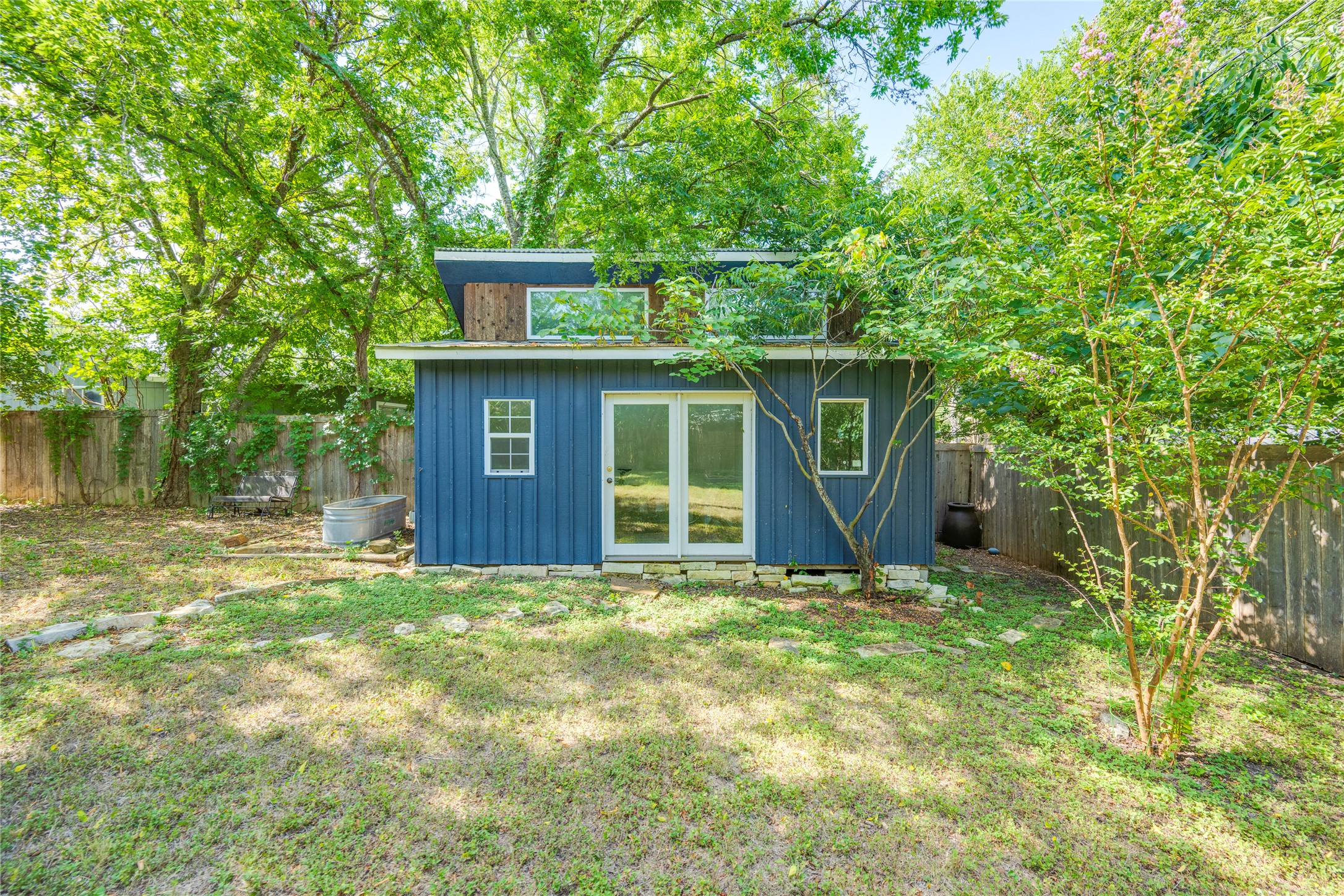 5300 Halmark Drive Austin, TX 78723 - Photo 27 of 40 A quaint blue shed with a modern sloped roof, nestled in a verdant backyard.