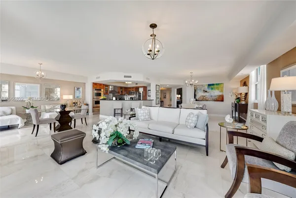 a living room with furniture kitchen view and a chandelier