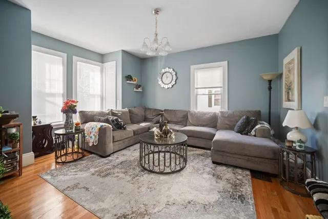 a living room with furniture a large window and a chandelier