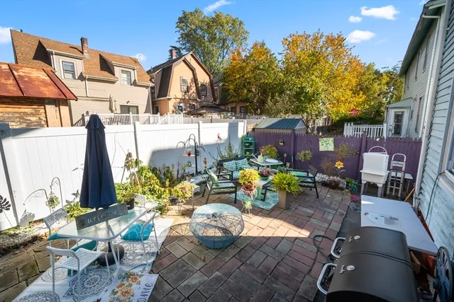 a view of a patio with table and chairs potted plants with wooden floor and fence