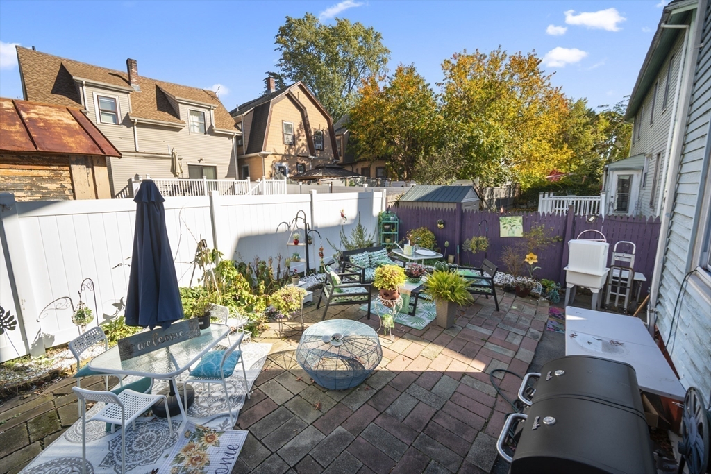 14-16 Dexter Street Lynn, MA 01902 - Photo 28 of 33 a view of a patio with table and chairs potted plants with wooden floor and fence