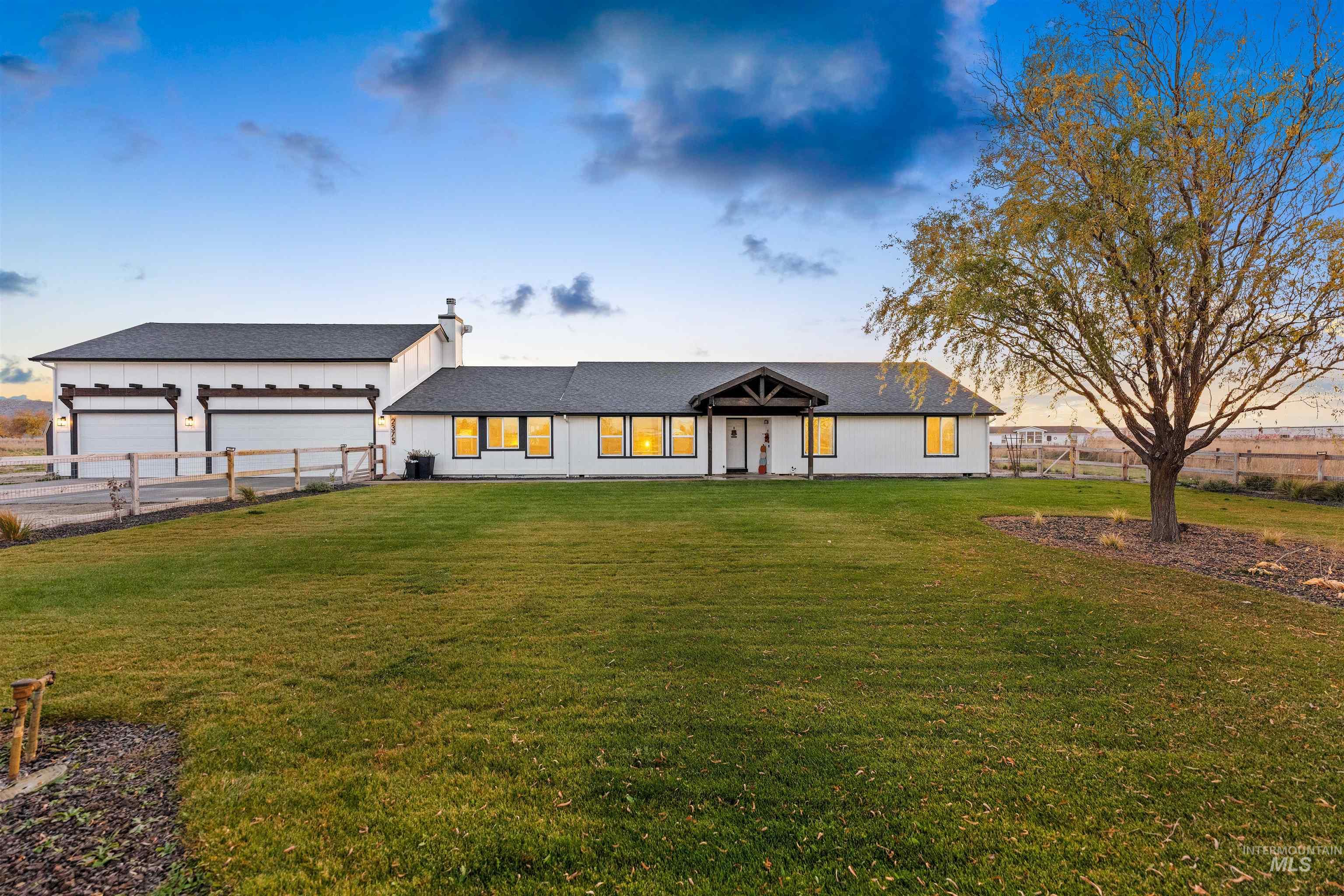 Modern farmhouse with a garage, a shingled roof, a chimney, and board and batten siding