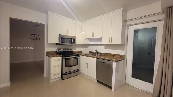 a kitchen with granite countertop white cabinets and stainless steel appliances