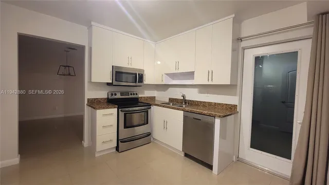 a kitchen with granite countertop white cabinets and stainless steel appliances