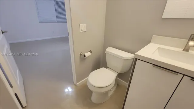 a white toilet sitting next to a white sink and vanity