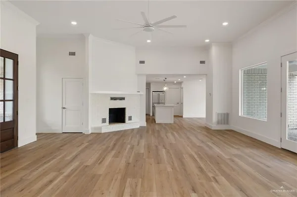 an empty room with wooden floor and a kitchen