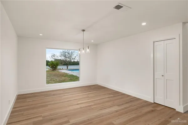 a large kitchen with kitchen island a sink a stove a refrigerator and white cabinets with wooden floor