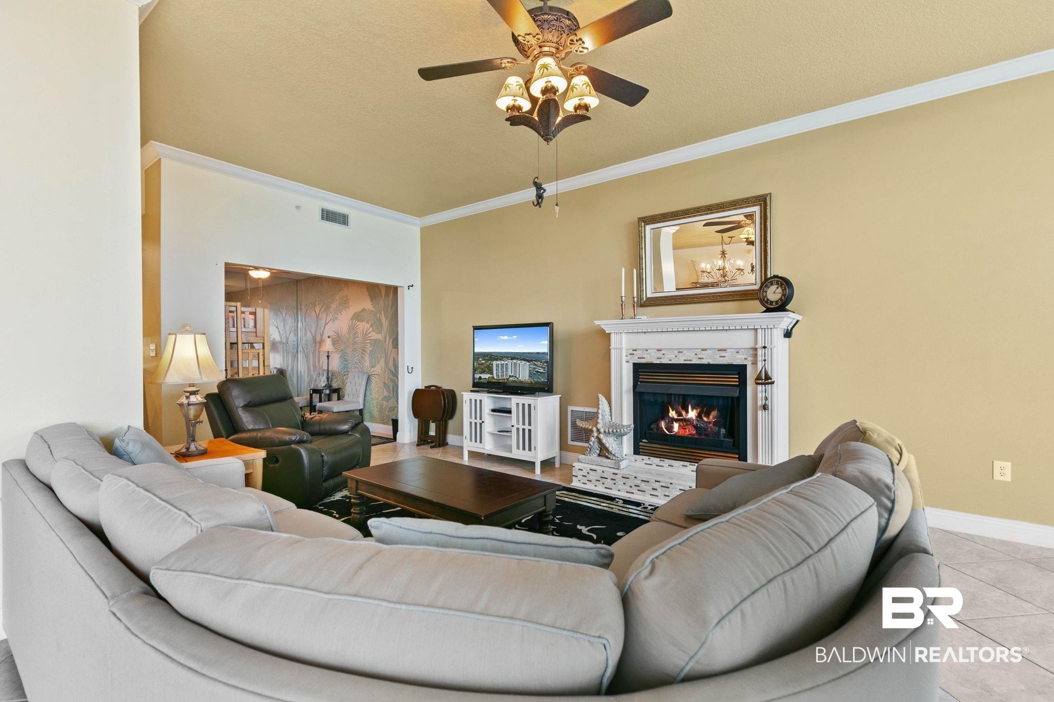 28250 Canal Road, Unit 208 Orange Beach, AL 36561 - Photo 10 of 53 Living room featuring ornamental molding, tile patterned flooring, ceiling fan, and a glass covered fireplace