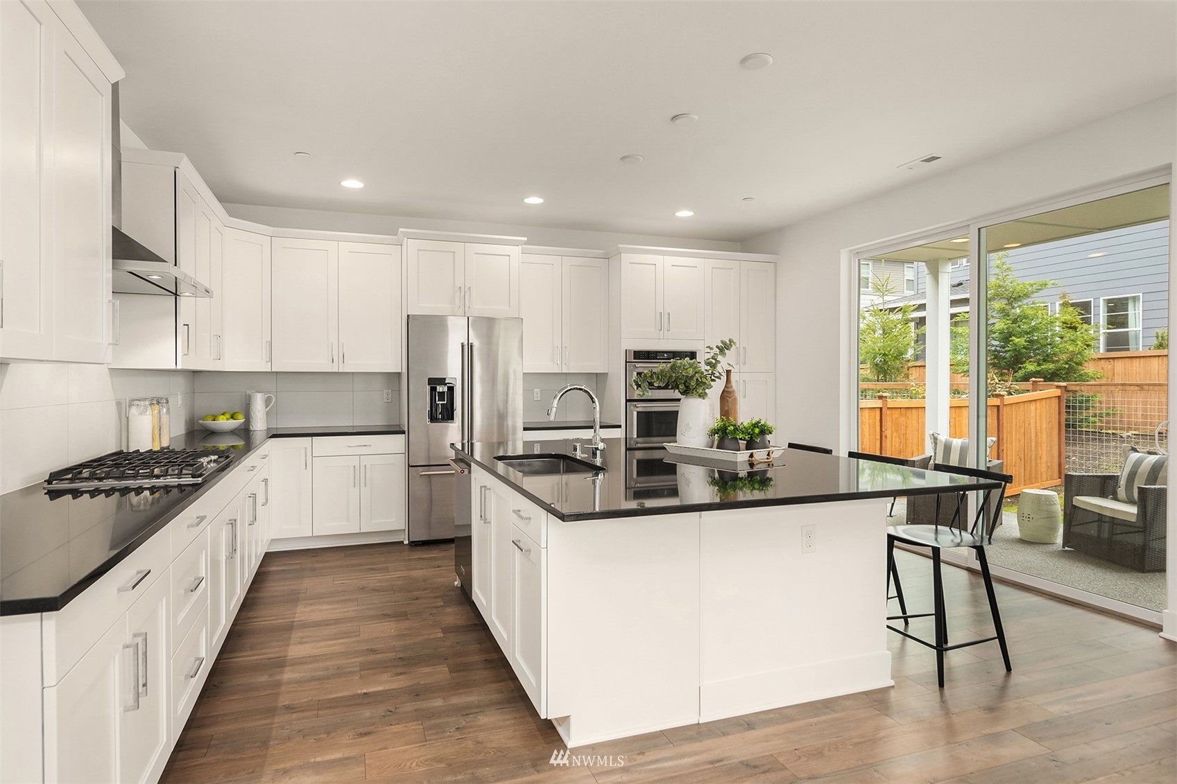 22127 44th Avenue Southeast Bothell, WA 98021 - Photo 9 of 38 a kitchen with stainless steel appliances kitchen island granite countertop a stove a sink a refrigerator and white cabinets with wooden floor