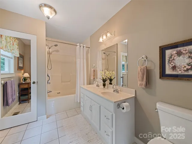 a bathroom with a double vanity sink a toilet a mirror and shower
