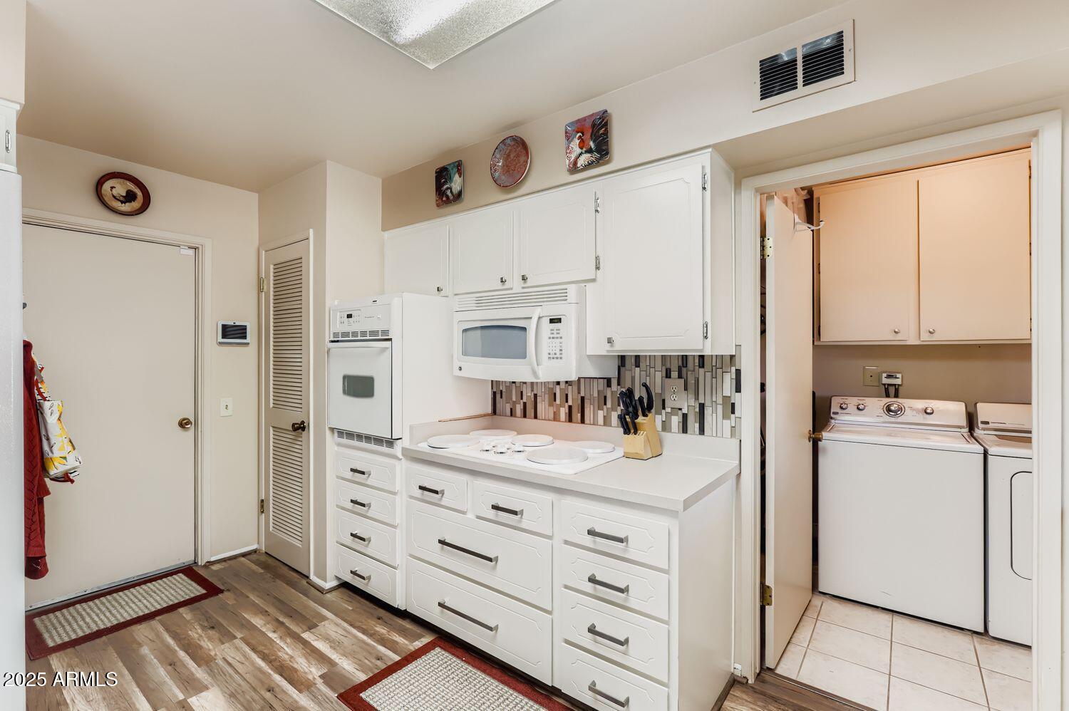 9524 West Greenway Road Sun City, AZ 85351 - Photo 15 of 25 a kitchen with a refrigerator and white cabinets