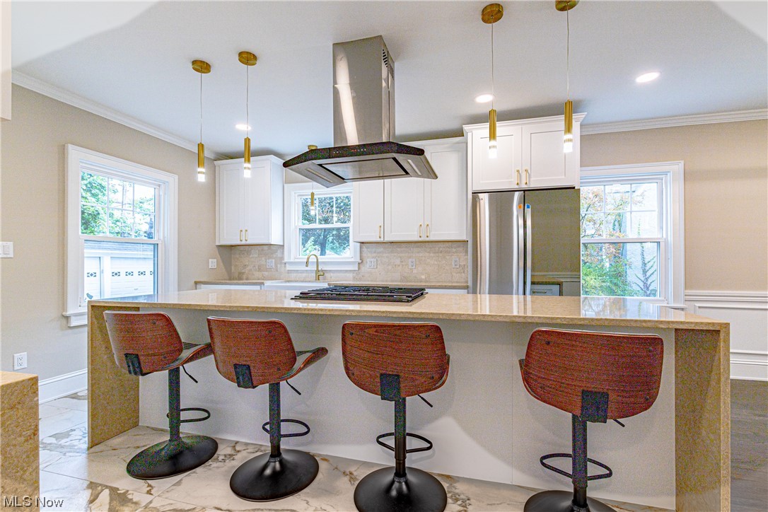 2923 Huntington Road Cleveland, OH 44120 - Photo 15 of 35 Kitchen featuring a wealth of natural light, backsplash, island exhaust hood, and pendant lighting
