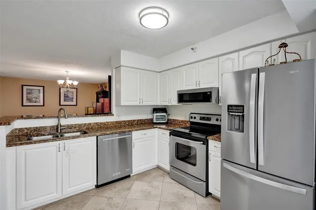 a kitchen with granite countertop stainless steel appliances white cabinets and a sink