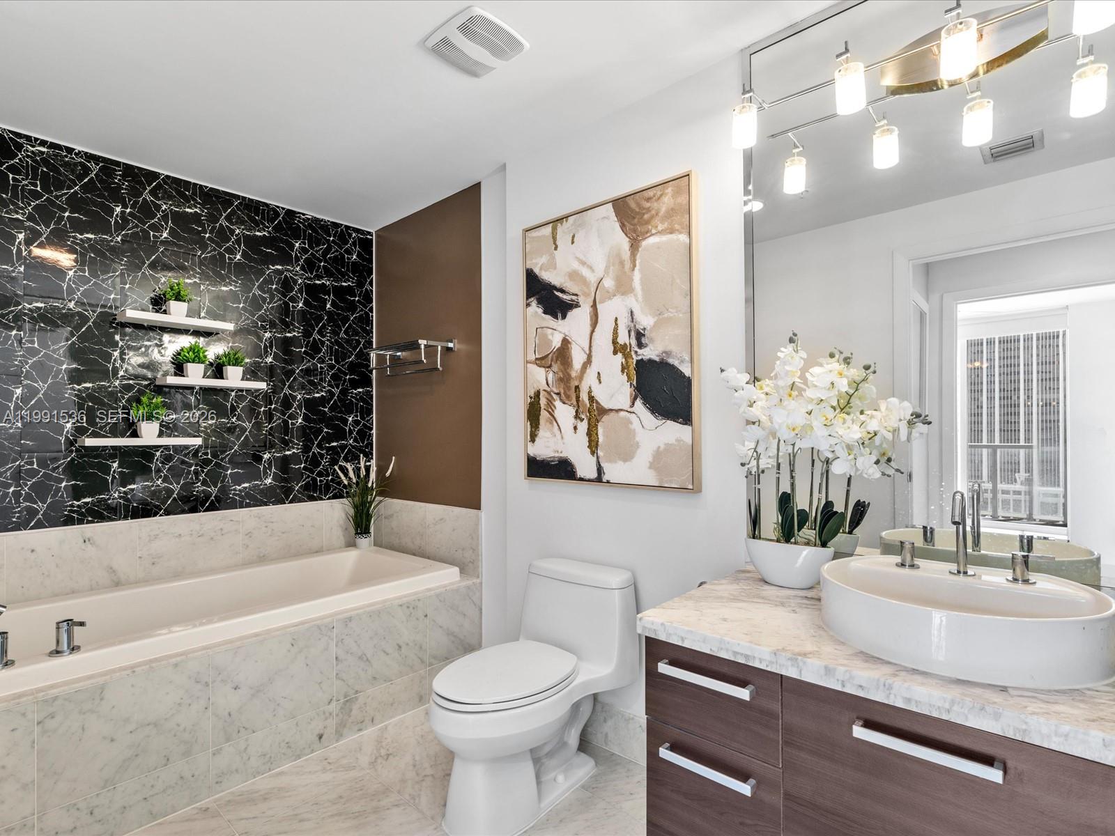 244 Biscayne Boulevard, Unit 1605 Miami, FL 33132 - Photo 17 of 46 a bathroom with a granite countertop sink a toilet a mirror a vanity a bathtub and shower