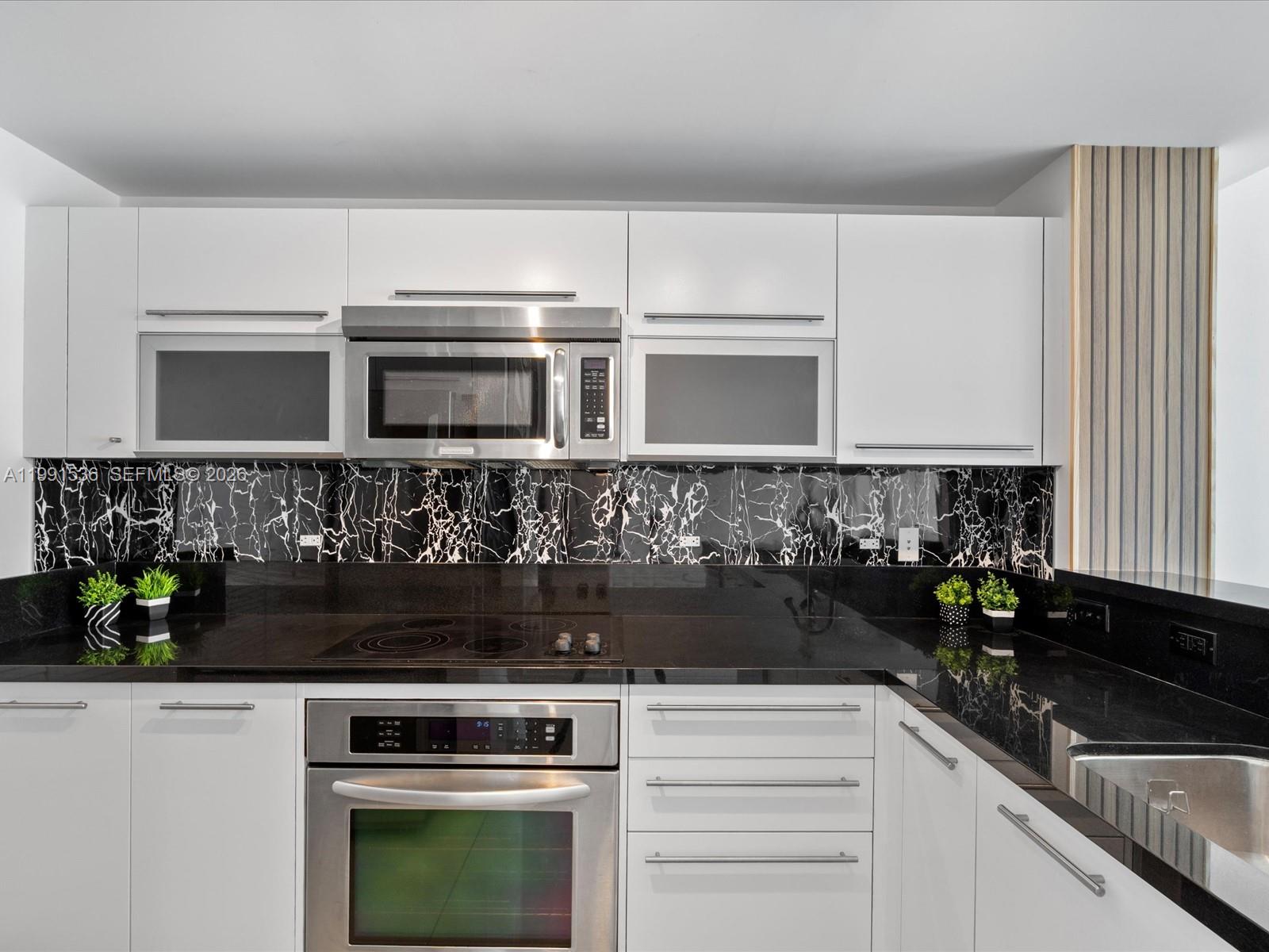 244 Biscayne Boulevard, Unit 1605 Miami, FL 33132 - Photo 4 of 46 a kitchen with granite countertop white cabinets and stainless steel appliances