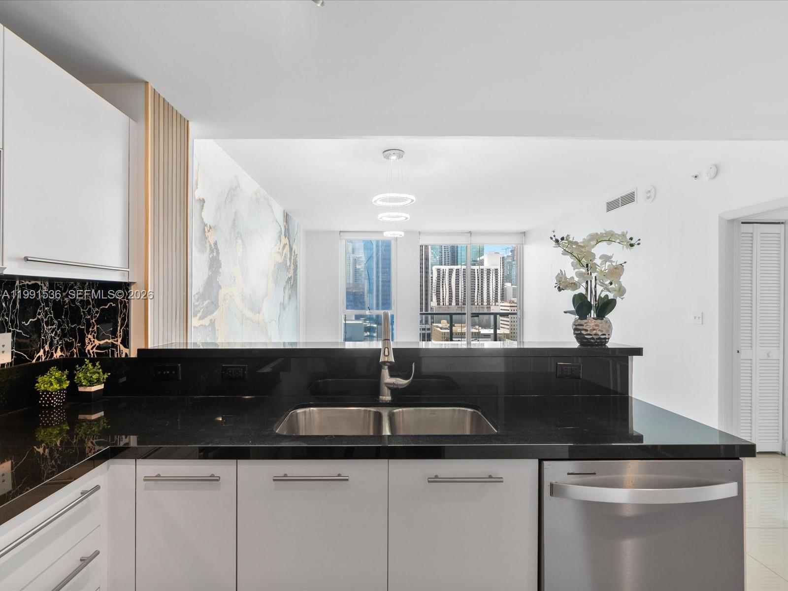 244 Biscayne Boulevard, Unit 1605 Miami, FL 33132 - Photo 5 of 46 a kitchen with granite countertop a sink and white cabinets
