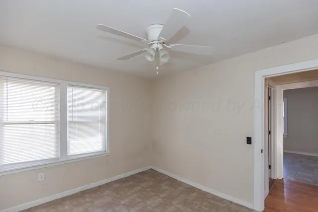 an empty room with a window and a fan